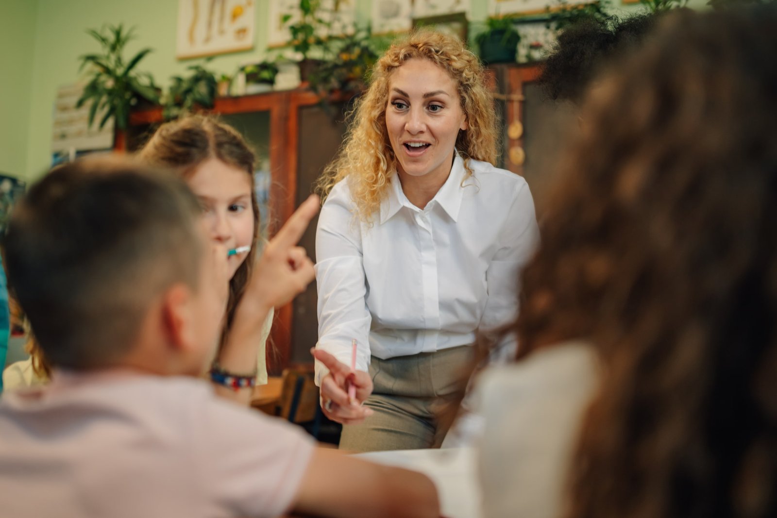 Profesora interactuando con un grupo de estudiantes en el aula utilizando la metodología comunicativa, fomentando la participación activa y el aprendizaje colaborativo mediante el diálogo y la resolución de preguntas en clase.
