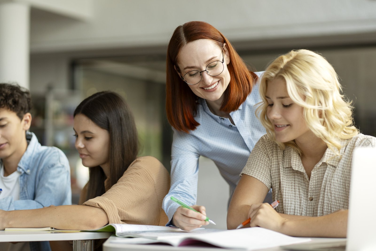 Profesora brindando seguimiento personalizado a estudiantes adultos durante una clase de inglés, resolviendo dudas y supervisando el progreso académico a través de interacción directa y apoyo individualizado.